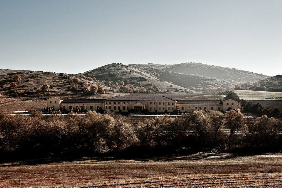 far view of 'Ktima Karipidis' building surrounded by trees and mountains in the background